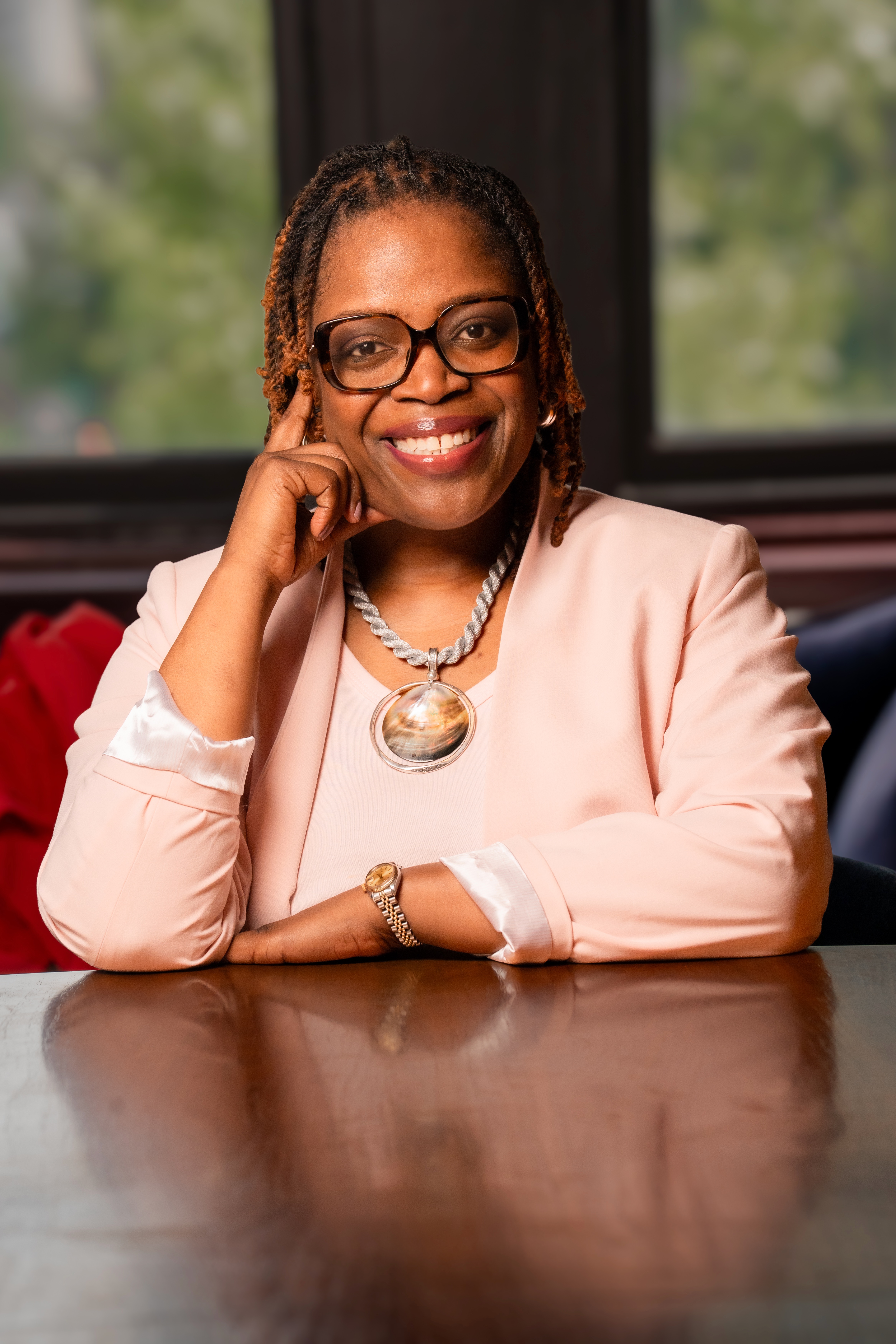 Janelle Renee Jenkins seated at a table in a blush jacket and glasses